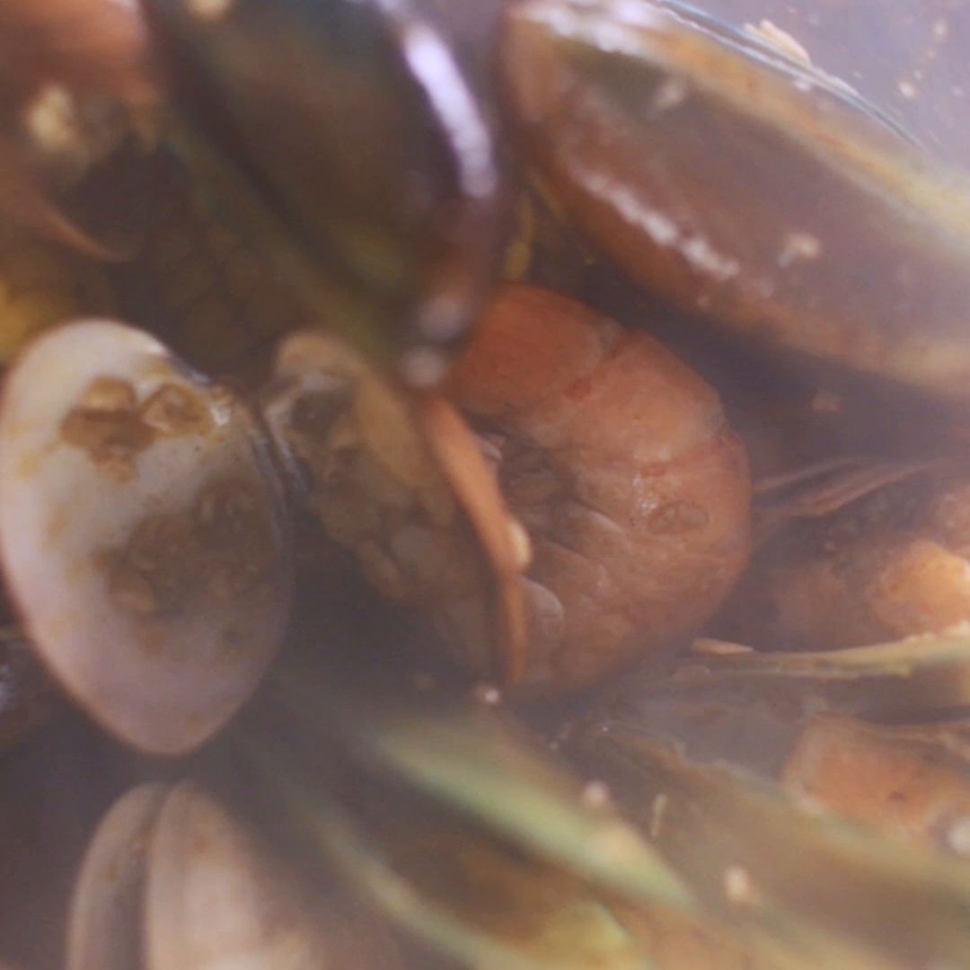 Clams, mussels and shrimp seen through the side of a steaming boil bag