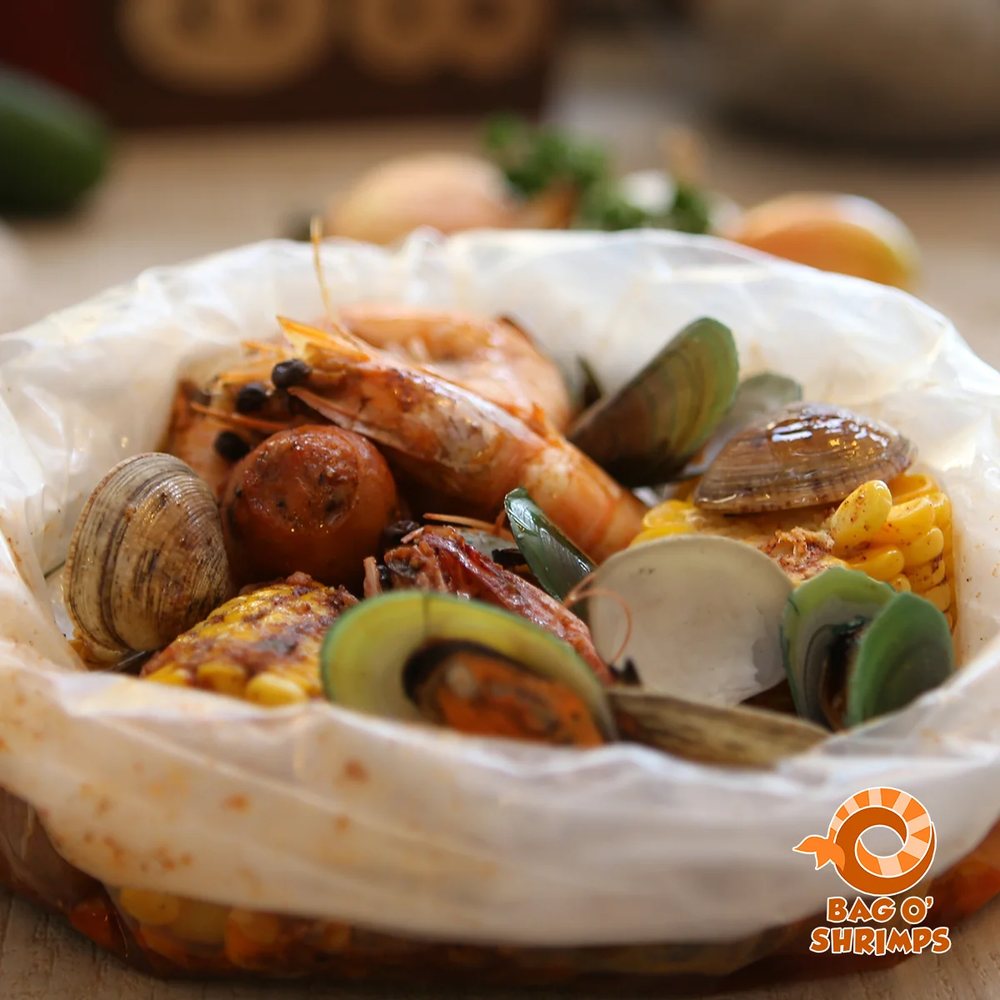 An open bag of shrimp, clams, mussels, sausage and corn