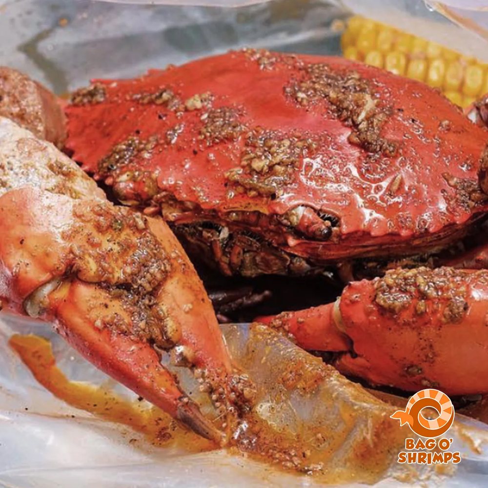 A whole crab glazed in garlicky sauce, with corn in the bag